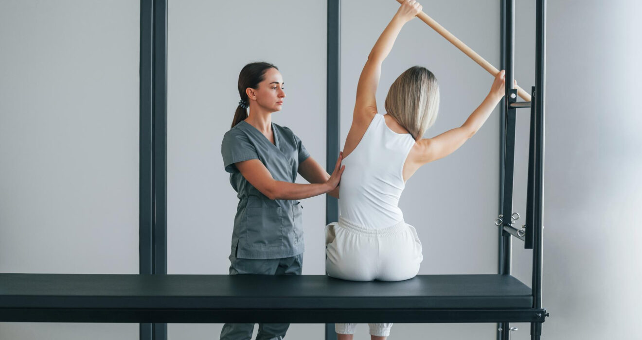 Fizyoterapist eşliğinde pilates yapan kadın.