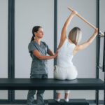 Fizyoterapist eşliğinde pilates yapan kadın.