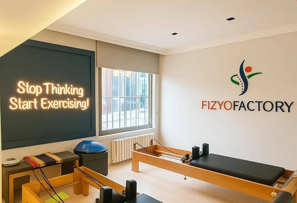 Fizyofactory pilates stüdyosunda reformer ekipmanları ve motivasyon yazısı bulunan modern egzersiz alanı.